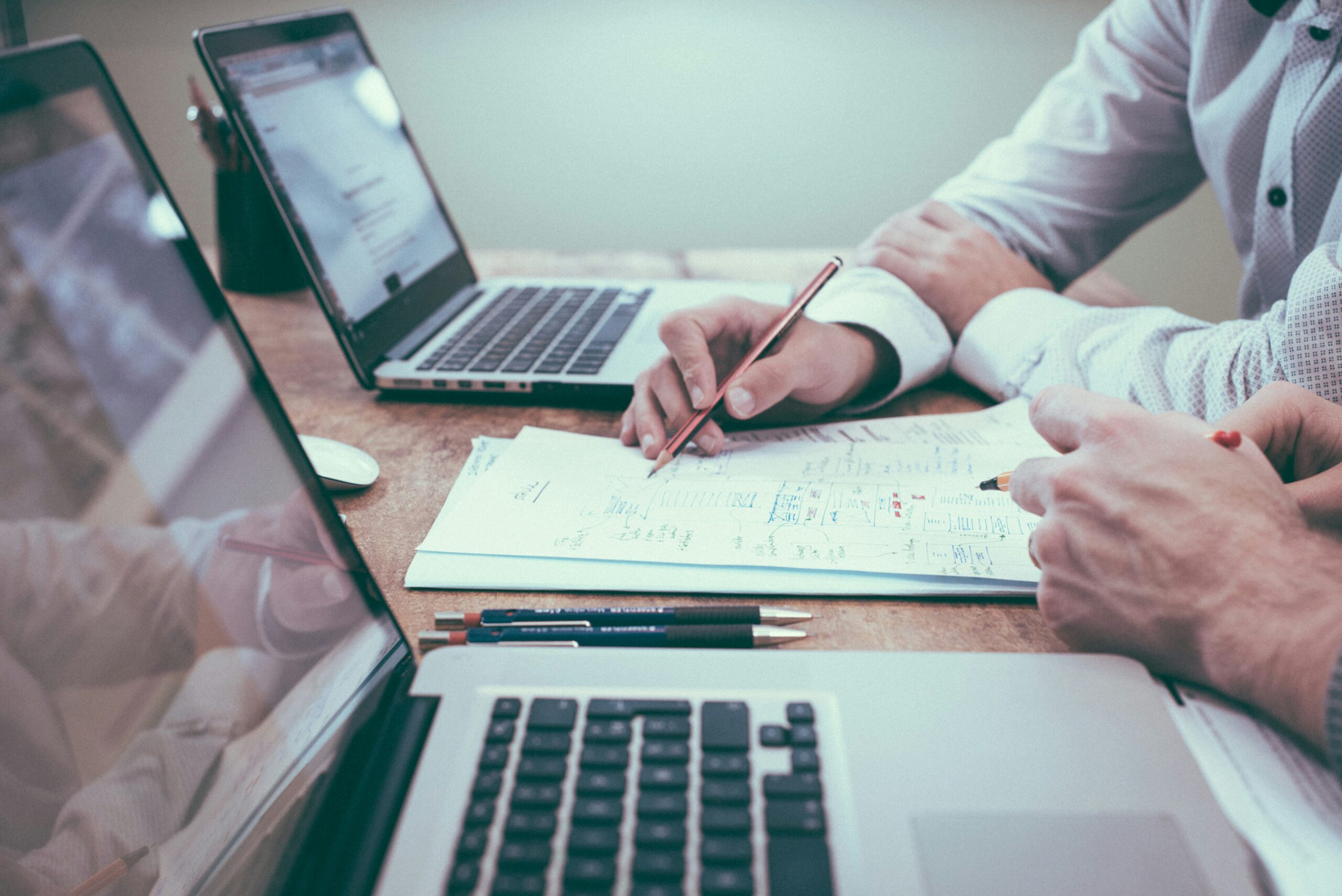 person holding pencil near laptop computer. How Backlinks can benefit your small business