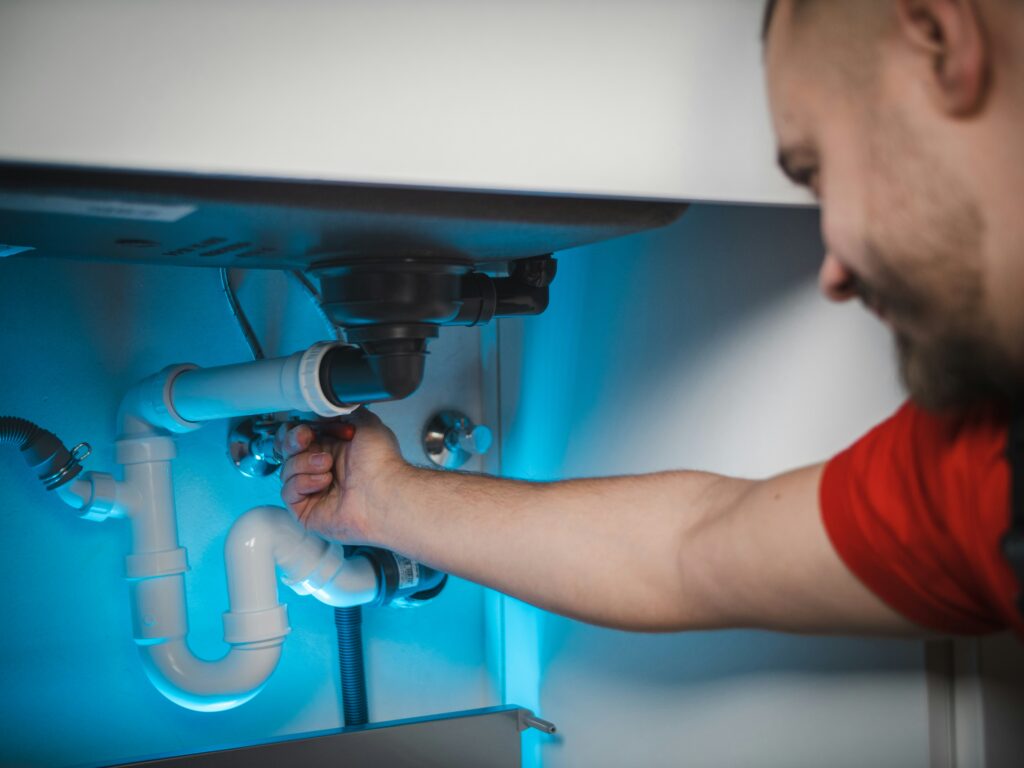 Plumber fixing kitchen sink pipes